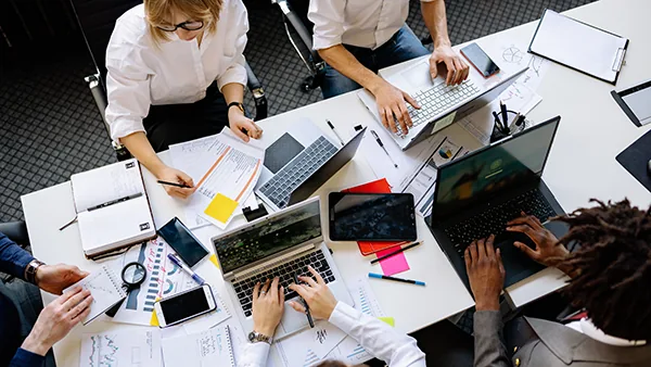 Team working together on laptops at a shared desk