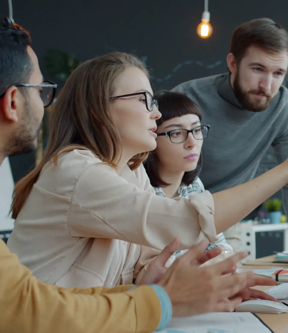 Colleagues discussing a project around a laptop
